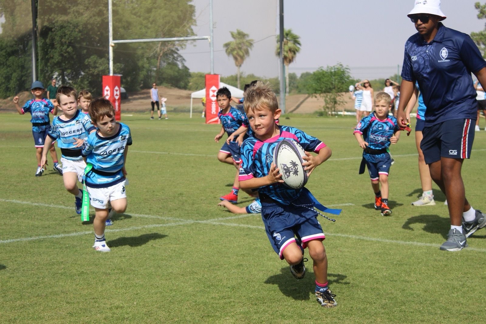 A young Dubai Warriors player runs with the ball at a tag rugby festival